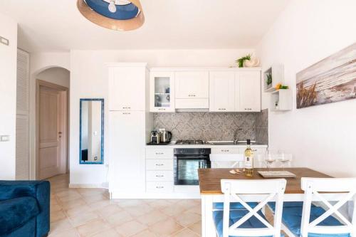 a kitchen with white cabinets and a table and chairs at Le Vele casa al mare panoramica in Castelsardo