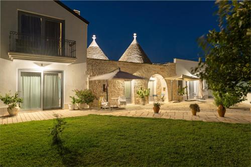 a house with a patio and a lawn at Trullisia Bed and Breakfast in Alberobello