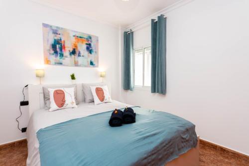 ein Schlafzimmer mit einem Bett mit zwei schwarzen Schuhen darauf in der Unterkunft Happy Waves Home in Las Palmas de Gran Canaria