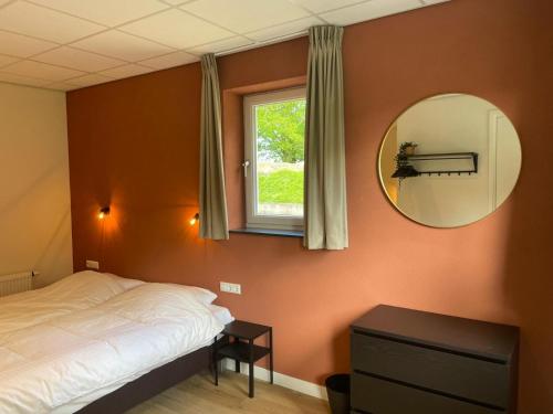 a bedroom with a bed and a mirror and a window at Brabantse Nacht in Deurne