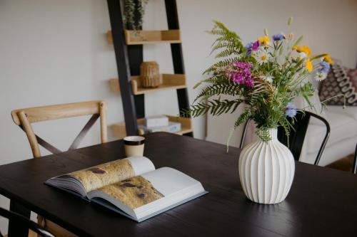 a vase of flowers and a book on a table at The Deerstone Luxury Eco Hideaway in Laragh