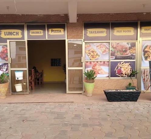 un restaurant avec des panneaux sur les fenêtres d'un bâtiment dans l'établissement Great Heights Motel, à Entebbe