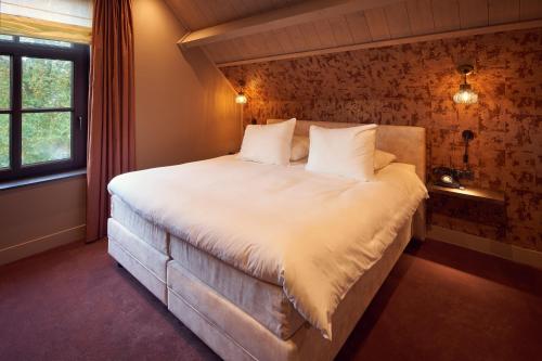 een slaapkamer met een groot wit bed en een raam bij The Yard hotel Noordkade in Veghel