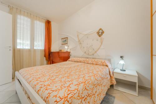a bedroom with a bed with an orange comforter at Villino Aloe - Goelba in Marina di Campo