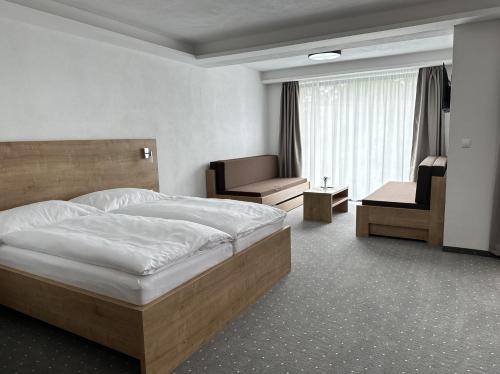 ein Hotelzimmer mit einem großen Bett und einem Stuhl in der Unterkunft Berg Liptov in Liptovský Mikuláš