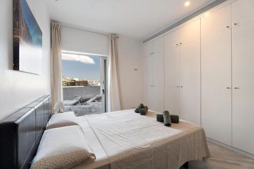 a white bedroom with a bed and a window at Villa en Hábitat del Duque in Adeje