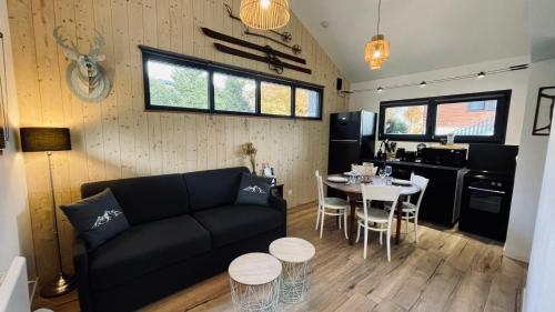 a living room with a black couch and a table at Le Chalet de la Plage in Sévrier