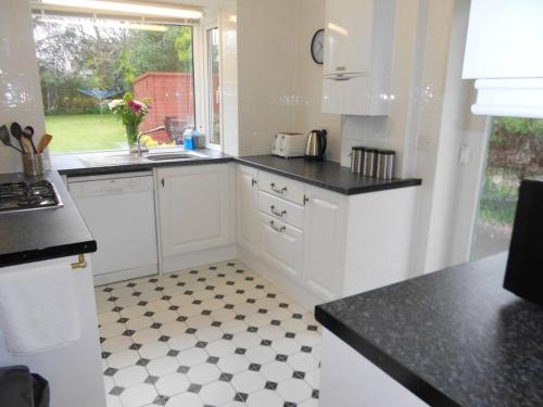 a kitchen with white cabinets and a black and white floor at BOURNECOAST: LOVELY BUNGALOW NEAR THE SEA - HB2087 in Bournemouth