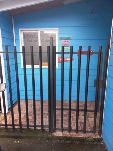 a black fence in front of a blue building at Cabañas y hostal sol de oriente in Puerto Montt