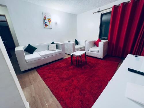 a living room with white couches and a red rug at Classic all ensuit 3 bedroom in kisumu town in Kisumu