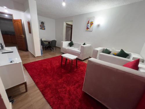 sala de estar con sofás blancos y alfombra roja en Classic all ensuit 3 bedroom in kisumu town, en Kisumu