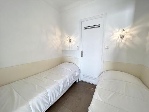 Duas camas num quarto com paredes brancas em Appartement Cannes, 2 pièces, 4 personnes - FR-1-470-11 em Cannes