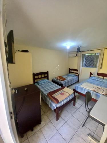 a room with two beds and a table and a desk at Hotel em SBO - Centro in Santa Bárbara dʼOeste