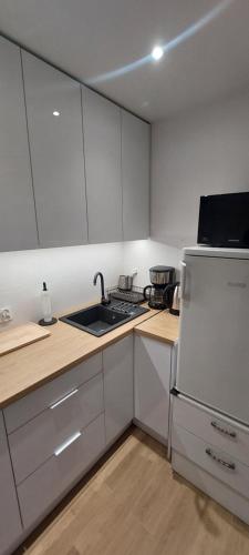 a kitchen with white cabinets and a white refrigerator at Apartament Koszutka - 100m od Spodka in Katowice