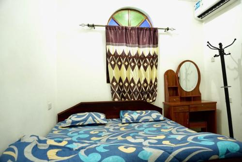 a bedroom with a bed with a curtain and a mirror at Rafiki Guest House in Ngambo