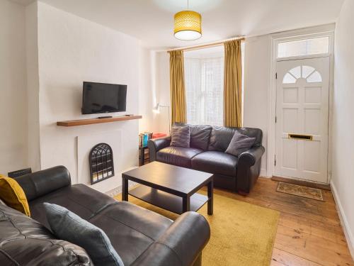 a living room with a leather couch and a fireplace at Host & Stay - Saint Peters in Canterbury