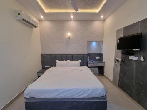 um quarto com uma cama e uma televisão de ecrã plano em Green Villa em Udaipur