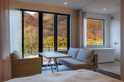 um quarto com um sofá, uma mesa e janelas em R;MOGAMI 