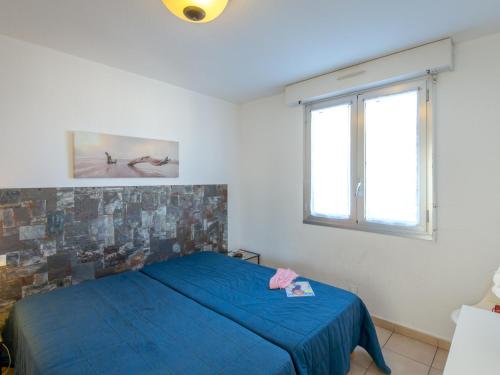 une chambre avec un lit bleu et une fenêtre dans l'établissement Appartement climatisé avec terrasse, à 50m de la plage et proche commerces, gare et centre-ville. - FR-1-466A-9, à Saint-Raphaël