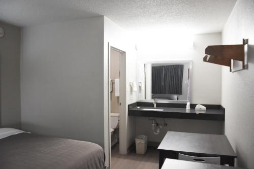 a bedroom with a bed and a sink and a mirror at Bridgeview Inn Chicago Area in Bridgeview