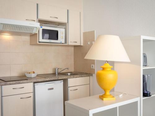 une cuisine avec une lampe jaune assise sur une table dans l'établissement Studio climatisé proche plage et commerces avec WiFi - FR-1-466A-31, à Saint-Raphaël