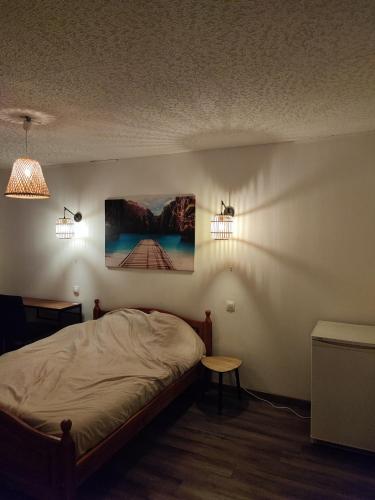 a bedroom with a bed and two lights on the wall at Grande Chambre Cosy avec Salle de Bain Privative in Lassigny
