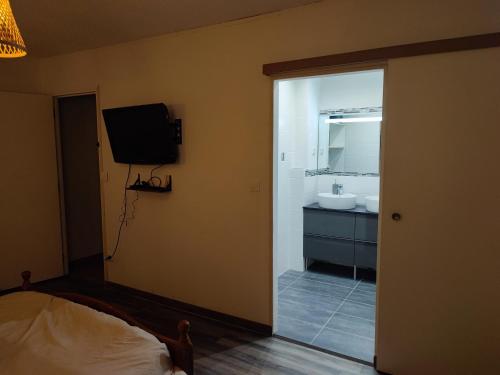 a bedroom with a bathroom with a sink and a television at Grande Chambre Cosy avec Salle de Bain Privative in Lassigny