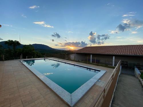 a swimming pool with a sunset in the background at Rancho Chega Mais 1 in Carmo do Rio Claro