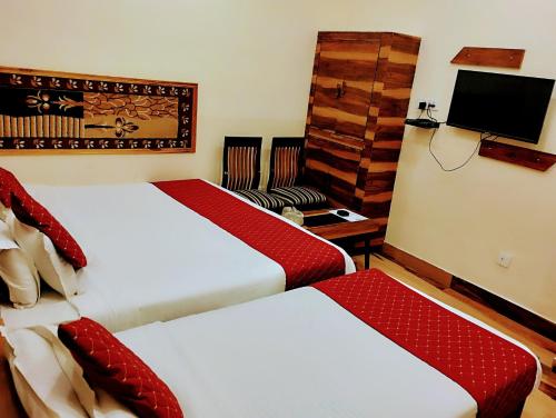 a hotel room with two beds and a tv at Bhagyashree Guest House in Varanasi