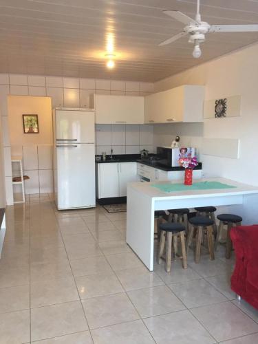 uma cozinha com electrodomésticos brancos e um balcão com bancos em Apartamento em Penha-SC em Penha