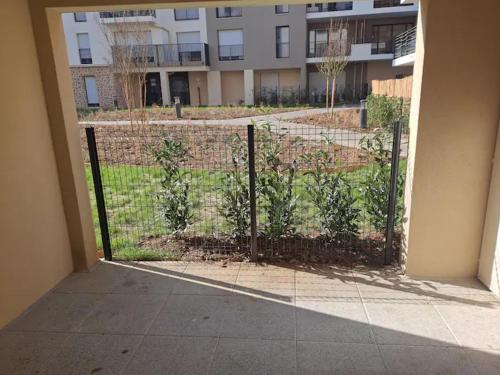 une clôture avec des plantes devant un bâtiment dans l'établissement Chez David, à Villejuif