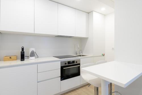 a white kitchen with white cabinets and a sink at Fafel Little House in Lamego