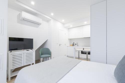 a white bedroom with a bed and a kitchen at Fafel Little House in Lamego