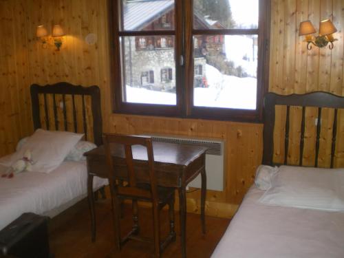 a room with two beds and a table and a window at Grand Chalet au pays du Mont Blanc in Vallorcine