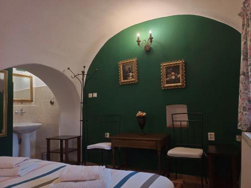 a bedroom with a green wall with a bed and a sink at Guest House Olšakovský in Český Krumlov