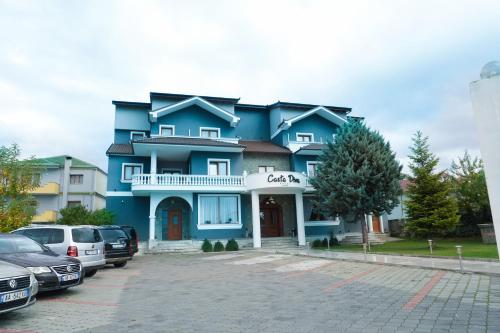 un edificio blu con auto parcheggiate in un parcheggio di Casta Diva Boutique Hotel a Korçë