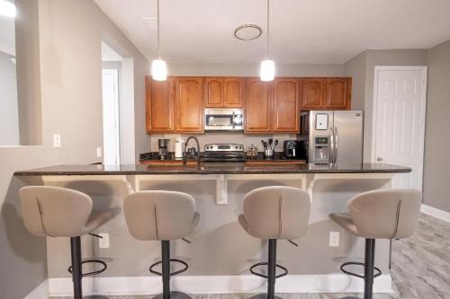 a kitchen with wooden cabinets and a counter with bar stools at DISNEY PARKS- International Dr - Orlando Luxury Condominium- Fully Equipped - 3bed & 2 bath- in Orlando