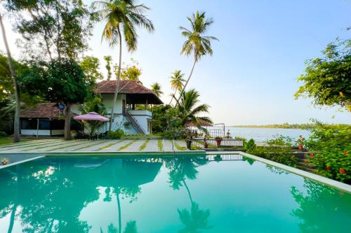 a villa with a pool and a view of the water at Jai Lake House in Perumbalam