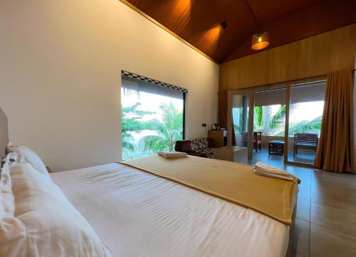 a bedroom with a large bed and a large window at Jai Lake House in Perumbalam