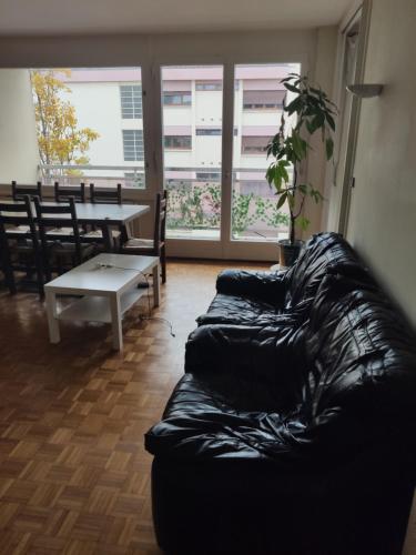 un soggiorno con divano nero e tavolo di City Break - Room Chambre Geneva ad Annemasse