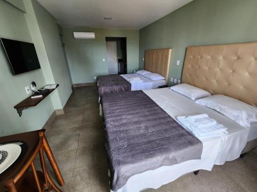 ein Hotelzimmer mit 2 Betten und einem Waschbecken in der Unterkunft Studio charmoso em Ponta Negra in Natal