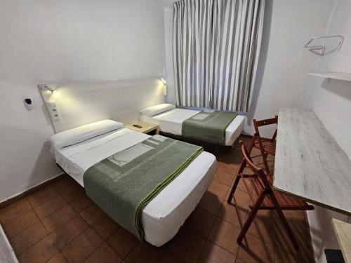 a hotel room with two beds and a table at Casa de Huéspedes Almansa in Madrid
