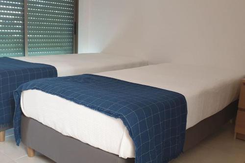 2 Betten mit blauer und weißer Bettwäsche in einem Zimmer in der Unterkunft Casa Praia Patroves in Patroves
