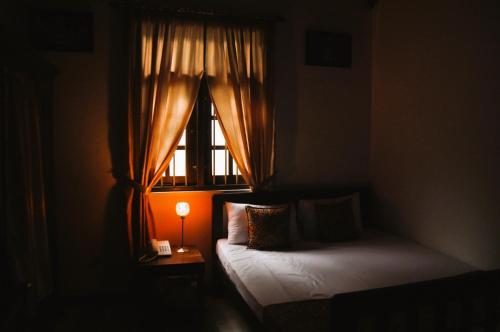 a bedroom with a bed and a window with a lamp at Muduna Walawwa Resort in Kandy