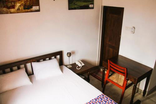 a bedroom with a bed and a desk and a phone at Muduna Walawwa Resort in Kandy