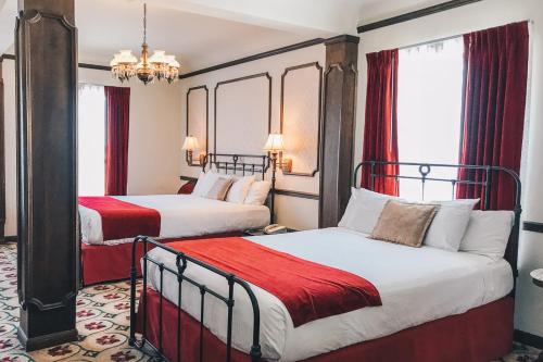 two beds in a hotel room with red curtains at Mizpah Hotel in Tonopah