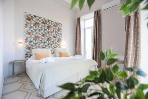 1 Schlafzimmer mit einem weißen Bett mit einem floralen Kopfteil in der Unterkunft DOMUS MARINA Rooms in Neapel