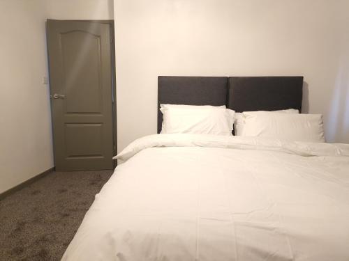 a white bed with white sheets and a black headboard at Walker Lodge in Oldbury