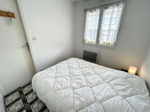 une chambre avec un lit blanc et une fenêtre dans l'établissement Appartement en front de mer avec balcon et parking privatif - FR-1-361-360, à Jullouville