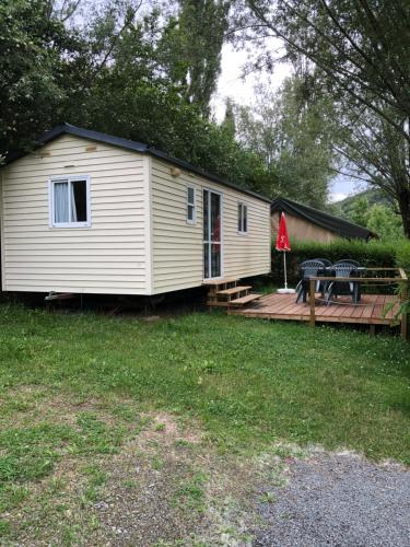a small white cabin with a wooden deck at Camping Du Pont De St Gal in Saint-Gal-sur-Sioule